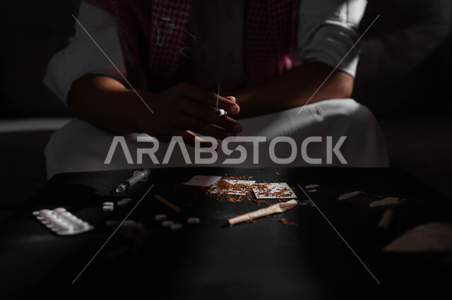 الادمان على تدخين التبغ والسجائر، تعاطي مواد ضارة وسامة، اتباع عادات سلوكية خاطئة، الإصابه بأمراض الجهاز التنفسي، صورة مقربة لشاب عربي سعودي خليجي يرتدي الشماغ والثوب التقليدي يمسك بيده السيجارة