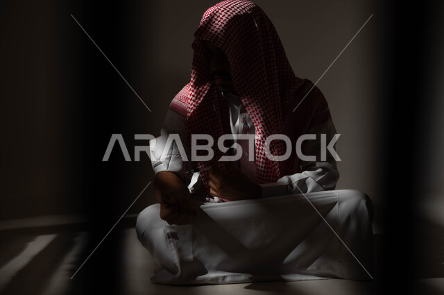 حقن المخدرات في الأوردة، الآثار السلبية للادمان والتعاطي، القيام بعادات سلوكية ضارة وتعاطي المواد السامة، المعاناة من الاضطرابات النفسية والمشاكل الصحية، بورتريه لرجل عربي خليجي سعودي يرتدي الشماغ والثوب التقليدي يجلس على الارض يقوم بأخذ جرعة مخدرة، خلفية سوداء