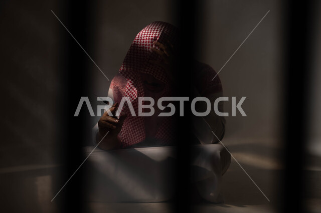 المعاناة من الاضطرابات النفسية والمشاكل الصحية، بورتريه لرجل عربي خليجي سعودي يرتدي الشماغ والثوب التقليدي يجلس على الارض يقوم بأخذ جرعة مخدرة، الآثار السلبية للادمان والتعاطي، حقن المخدرات في الأوردة، القيام بعادات سلوكية ضارة وتعاطي المواد السامة، خلفية سوداء