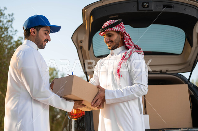 ايماءات الرضا والسعادة لاستلام الطلب بشكل سليم، صورة مقربة لشاب عربي سعودي خليجي يرتدي الزي التقليدي ويضع الشماغ يقوم بالتوقيع على استلام الطلب، كراتين الشحن والتوصيل الاونلاين، الوقوف امام سيارة شحن البضائع