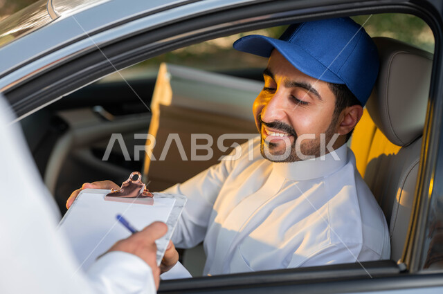 التوقيع على أوراق و مستندات استلام و تسليم الطرد, خدمات التوصيل السريعة في السعودية، تسليم البضائع و الطلبات للزبائن، صورة مقربة لمندوب توصيل عربي خليجي سعودي مبتسم يرتدي قبعة زرقاء يجلس داخل السيارة بإيماءات البشاشة والرضا
