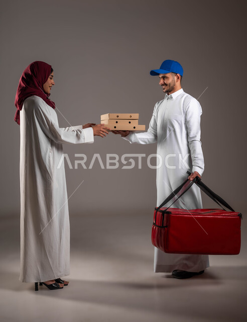 عملية شحن وتوصيل موثوقه وناجحة، بورتريه لرجل عربي خليجي سعودي يرتدي الزي التقليدي وقبعة زرقاء يمسك بيده حقيبة حمراء وكراتين طعام،  تسليم الطلب للزبونة بشكل سليم، صوره الجسم بالطول الكامل، خلفيه رماديه