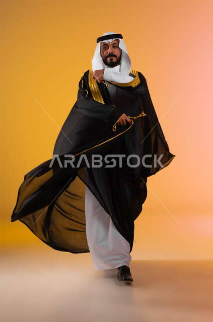 الأناقة والاهتمام بالمظهر الخارجي بليلة العرس, مفهوم التزين والاطلالة المتألقة، بورتريه لرجل عربي خليجي سعودي يرتدي الغترة التقليدية والبشت السعودي، ايماءات الحب والسعادة لبدء حياة جديدة، صورة لكامل الجسم، خلفية ملونة