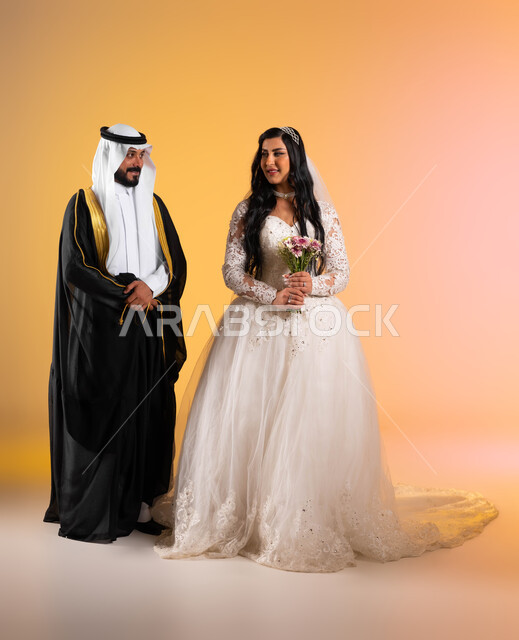 مراسم الأعراس وحفلات الزفاف في المملكة، مفهوم التزيين والاطلالة المتأنقة، بورتريه لعروس عربية خليجية سعودية مبتسمة ترتدي فستان الزفاف الأبيض تحمل بيدها باقة ورد تنظر الى زوجها بتعابير المودة, نظرات مليئة بالرومنسية والحب، صورة الجسم بالكامل، خلفية ملونة
