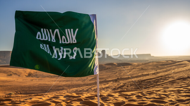 Pride, pride, and flaunting of the nation’s achievements and authenticity, the emblem of national identity and the banner of Islam and monotheism, the day of our religion 1727 AD, a close-up of the founding flag planted in the golden sand during the day, the anniversary of the founding of the first Saudi state on February 22