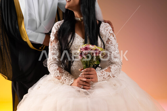 Love and affection between newlyweds, wedding parties in the Kingdom, the concept of stability and forming a family, a groom wearing a bisht and placing his hands on his wife’s shoulders, a portrait of a Saudi Arabian Gulf bride wearing a white wedding dress holding a bouquet of roses, a colorful background