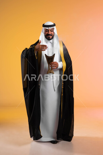 التطيب بالمسك والروائح العطرة، أصالة العادات والتقاليد السعودية، بورتريه لرجل عربي خليجي سعودي يرتدي البشت والغترة التقليدية ويمسك حامل البخور، استخدام خشب العود في الأعياد والمناسبات، الاهتمام بالمظهر الخارجي، صورة الجسم بالطول الكامل، خلفية ملونة