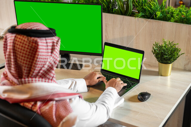 متابعة أخبار مواقع التواصل الإجتماعي، التطور التقني والتكنولوجي في مجالات مختلفة، البحث عن عمل عن طريق الإنترنت، صورة مقربة من الخلف لرجل عربي خليجي سعودي يقوم إنجاز المهام العملية عبر جهاز الحاسوب، أجهزة إلكترونية بشاشة خضراء فارغة، كروما