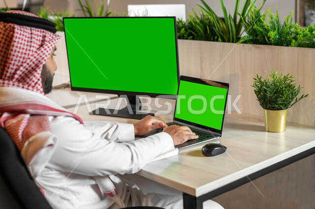 التطور التقني والتكنولوجي في مجالات مختلفة، البحث عن عمل عن طريق الإنترنت، صورة مقربة من الخلف لرجل عربي خليجي سعودي يقوم إنجاز المهام العملية عبر جهاز الحاسوب، متابعة أخبار مواقع التواصل الإجتماعي، أجهزة إلكترونية بشاشة خضراء فارغة، كروما