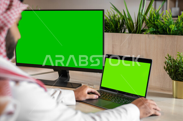 استعمال التكنولوجيا الحديثة والمتطورة للتعلم عن بعد، القيام بمقابلات وإجتماعات العمل أونلاين، صورة مقربة من الخلف لرجل عربي خليجي سعودي يقوم بمتابعة أخبار وسائل التواصل الإجتماعي، عرض شاشة خضراء فارغة على الأجهزة التقنية، كروما