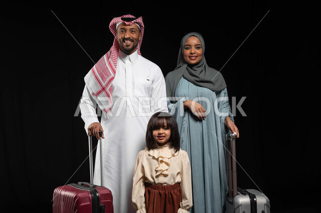الحفاظ على الترابط والاستقرار الأسري، بورتريه لعائلة عربية خليجية سعودية يقفون بجانب حقائب السفر ويقومون بالنظر إلى الكاميرا، الأجواء العائلية السعيدة المليئة بالحب، الاستعداد لقضاء إجازة صيفية والذهاب برحلة سياحية ممتعة مع الأهل، خلفية سوداء