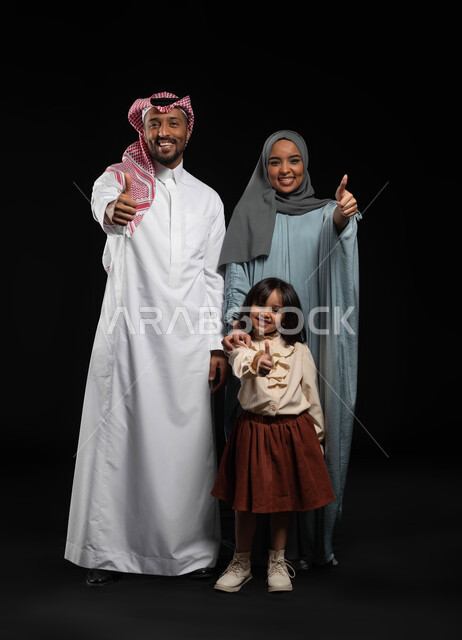 ايماءات الاعجاب والقبول، رعاية الأم لأطفالها والاهتمام بهم, بورتريه لعائلة عربية خليجية سعودية مبتسمة ترفع اصابع الابهام للاعلى  بعلامة الجودة ، الترابط الأسري والحفاظ على الاستقرار العائلي، صوره الجسم بالطول الكامل، خلفيه سوداء