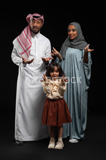 الشعور بالحيرة والتساؤل حول أمر ما، التردد وعدم الثقة بخصوص موضوع معين، بورتريه لعائلة علربية خليجية سعودية يرفعون كفيهم بايماءات عدم التأكد والدهشة، الوقوف باستقامة والنظر الى الكاميرا، صورة الجسم بالطول الكامل، خلفية سوداء