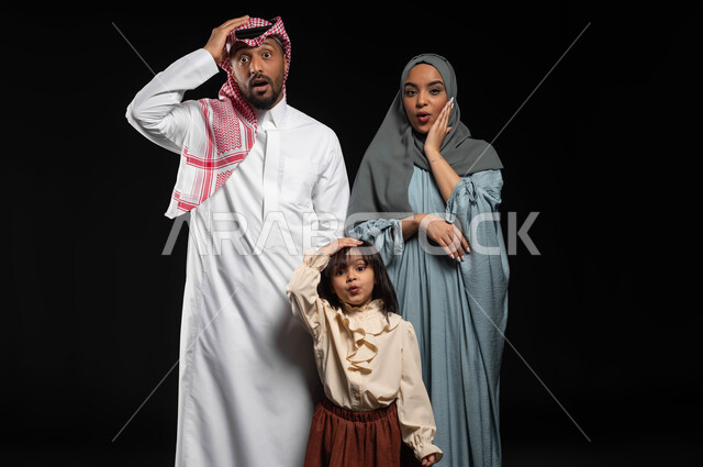 النظر الى الكاميرا بايماءات وحركات وجه ويدين تدل على الذعر والخوف، بورتريه لعائلة عربيه خليجية سعودية يرفعون أيديهم بتعابير الدهشة والذهول، المفاجئة والدهشة لرؤية شيء ما، خلفية سوداء
