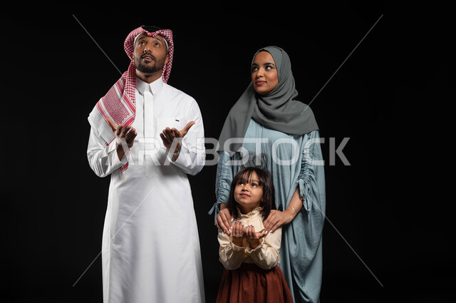 التقرب إلى الله تعالى بالدعاء والتضرع له, بورتريه لعائلة عربية خليجية سعودية يرفعون أيديهم وينظرون للسماء, مفهوم تربية الصالحة للأبناء على الطاعة والعبادة, الحمد والشكر وطلب المغفرة, بناء مجتمع سعودي متنامي, خلفية سوداء