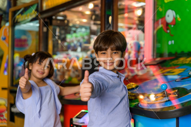 طفلان سعوديان في مدينة الألعاب ، يلعبان العديد من الألعاب الالكترونية المتنوعة و المسلية ، قضاء اوقات رائعة في مدينة الملاهي ، العاب الكترونية ، التسلية و الترفيه ، الترفيه في العطلة الصيفية