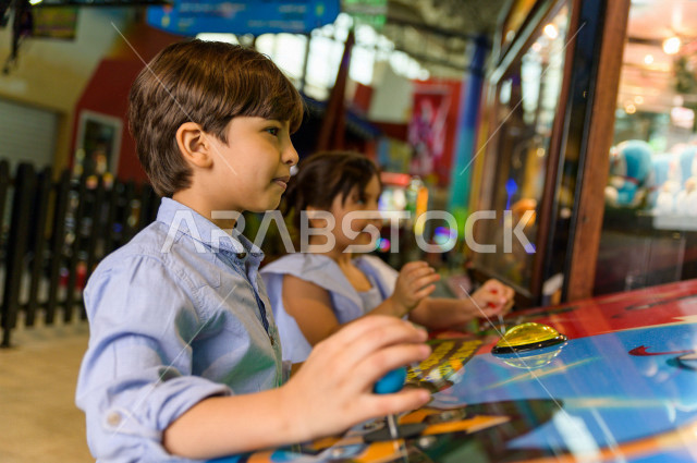 طفلان سعوديان في مدينة الألعاب ، يلعبان العديد من الألعاب الالكترونية المتنوعة و المسلية ، قضاء اوقات رائعة في مدينة الملاهي ، العاب الكترونية ، التسلية و الترفيه ، الترفيه في العطلة الصيفية