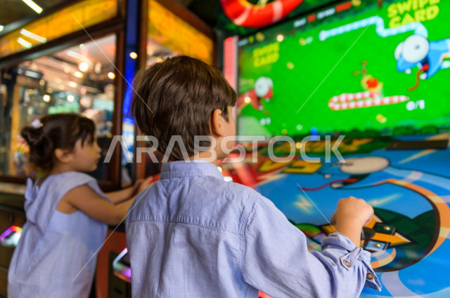 طفلان سعوديان في مدينة الألعاب ، يلعبان العديد من الألعاب الالكترونية المتنوعة و المسلية ، قضاء اوقات رائعة في مدينة الملاهي ، العاب الكترونية ، التسلية و الترفيه ، الترفيه في العطلة الصيفية