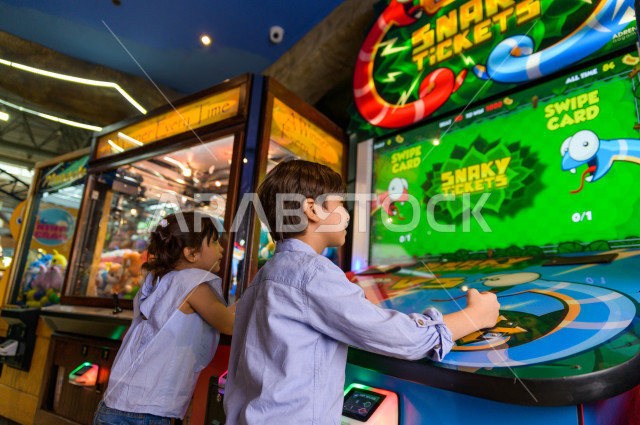 طفلان سعوديان في مدينة الألعاب ، يلعبان العديد من الألعاب الالكترونية المتنوعة و المسلية ، قضاء اوقات رائعة في مدينة الملاهي ، العاب الكترونية ، التسلية و الترفيه ، الترفيه في العطلة الصيفية