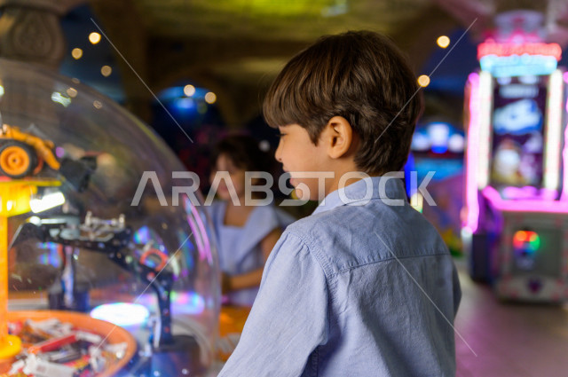 طفلان سعوديان في مدينة الألعاب ، يلعبان العديد من الألعاب الالكترونية المتنوعة و المسلية  ، قضاء اوقات رائعة في مدينة الملاهي ، العاب الكترونية ، التسلية و الترفيه ، الترفيه في العطلة الصيفية