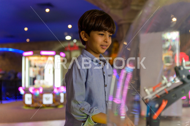 A Saudi child in the city of games, plays many different electronic games, spending great times in the amusement park, electronic games, entertainment and entertainment, entertainment in the summer vacation