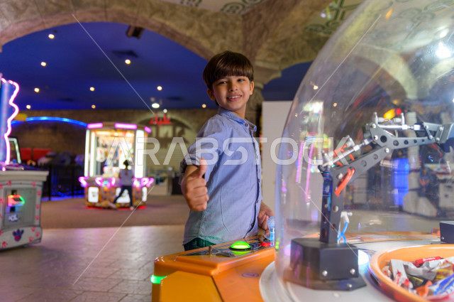 A Saudi child in the city of games, plays many different electronic games, spending great times in the amusement park, electronic games, entertainment and entertainment, entertainment in the summer vacation