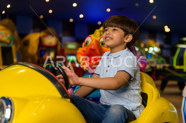 طفل سعودي في مدينة الألعاب ، يلعب العديد من الألعاب الالكترونية المتنوعة  ، قضاء اوقات رائعة في مدينة الملاهي ، العاب الكترونية ، التسلية و الترفيه ، الترفيه في العطلة الصيفية