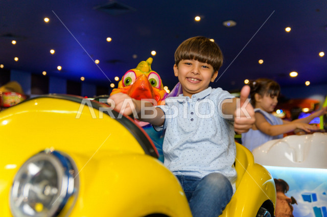 طفل سعودي في مدينة الألعاب ، يلعب العديد من الألعاب الالكترونية المتنوعة  ، قضاء اوقات رائعة في مدينة الملاهي ، العاب الكترونية ، التسلية و الترفيه ، الترفيه في العطلة الصيفية