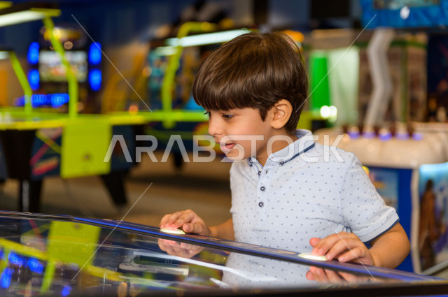 طفل سعودي في مدينة الألعاب ، يلعب العديد من الألعاب الالكترونية المتنوعة  ، قضاء اوقات رائعة في مدينة الملاهي ، العاب الكترونية ، التسلية و الترفيه ، الترفيه في العطلة الصيفية