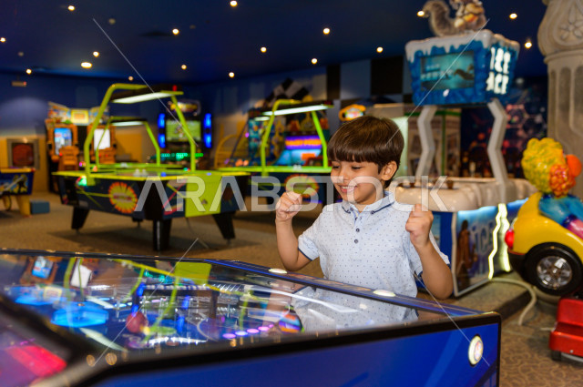 طفل سعودي في مدينة الألعاب ، يلعب العديد من الألعاب الالكترونية المتنوعة  ، قضاء اوقات رائعة في مدينة الملاهي ، العاب الكترونية ، التسلية و الترفيه ، الترفيه في العطلة الصيفية