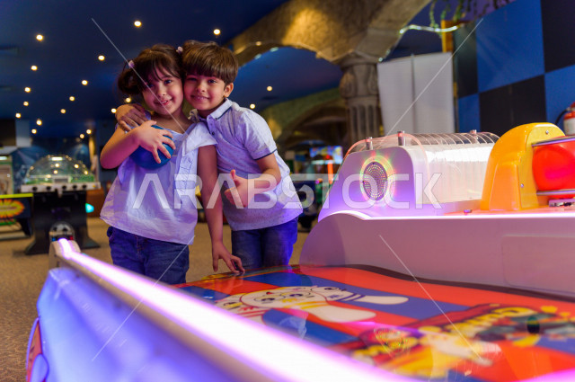 طفلان سعوديان في مدينة الألعاب ، يلعبان العديد من الألعاب الالكترونية المتنوعة و المسلية ، قضاء اوقات رائعة في مدينة الملاهي ، العاب الكترونية ، التسلية و الترفيه ، الترفيه في العطلة الصيفية