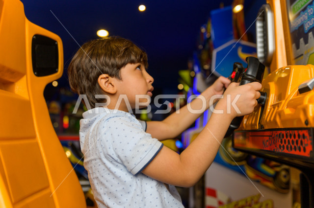 طفل سعودي في مدينة الألعاب ، يلعب العديد من الألعاب الالكترونية المتنوعة  ، قضاء اوقات رائعة في مدينة الملاهي ، العاب الكترونية ، التسلية و الترفيه ، الترفيه في العطلة الصيفية