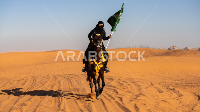 استذكار العيد الوطني في 23 سبتمبر, شغف وعشق الخيول الأصيلة, فارسة عربية خليجية سعودية ترتدي البرقع والعباءة السوداء تمتطي فرس بني أصيل وتمسك علم المملكة باعتزاز في يوم العلم 11 مارس, يوم بدينا 1727م, ذكرى تأسيس الدولة السعودية الأولى في 22 فبراير