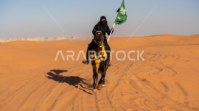 ذكرى تأسيس الدولة السعودية الأولى في 22 فبراير, شغف وعشق الخيول الأصيلة, فارسة عربية خليجية سعودية ترتدي البرقع والعباءة السوداء تمتطي فرس بني أصيل وتمسك علم المملكة باعتزاز في يوم العلم 11 مارس, يوم بدينا 1727م, استذكار العيد الوطني في 23 سبتمبر