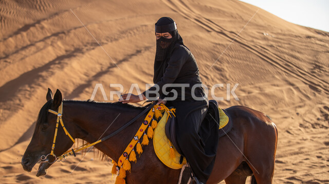 الاستمتاع بممارسة الهوايات التقليدية, التجول على الرمال الذهبية الناعمة في إحدى صحاري المملكة, فارسة عربية خليجية سعودية ترتدي البرقع والعباءة السوداء تمتطي فرس بني أصيل, يوم بدينا 1727م, ذكرى تأسيس الدولة السعودية الأولى في 22 فبراير