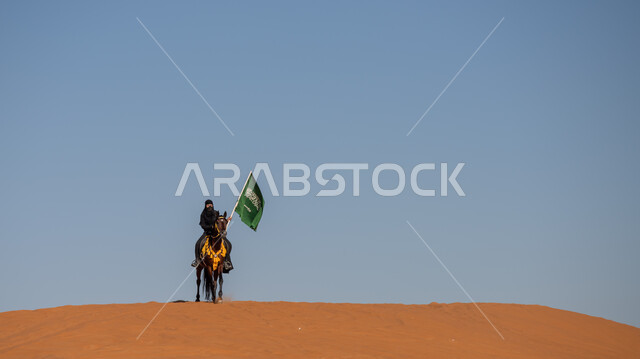  إحياء التراث السعودي التقليدي الشعبي، رفع علم المملكة في اليوم الوطني في 23 سبتمبر, يوم بدينا 1727م, ذكرى تأسيس الدولة السعودية الأوى في 22 فبراير, فارسة عربية خليجية سعودية ترتدي العباءة السوداء تمتطي فرس بني أصيل, يوم العلم 11 مارس