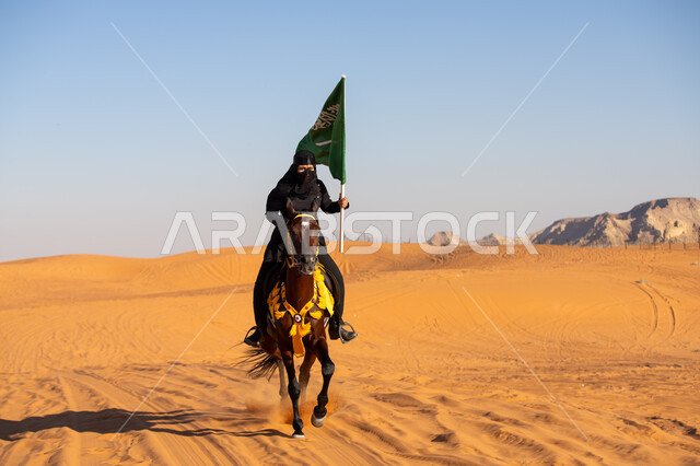 استذكار العيد الوطني في 23 سبتمبر, شغف وعشق الخيول الأصيلة, فارسة عربية خليجية سعودية ترتدي البرقع والعباءة السوداء تمتطي فرس بني أصيل وتمسك علم المملكة باعتزاز في يوم العلم 11 مارس, يوم بدينا 1727م, ذكرى تأسيس الدولة السعودية الأولى في 22 فبراير
