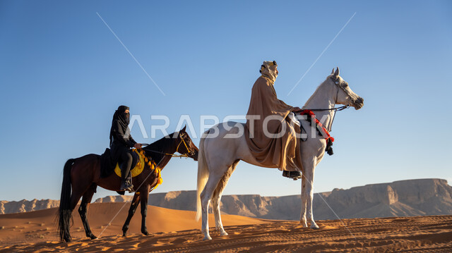 أصالة وقوة الحصان العربي، فعاليات وأنشطة ركوب الجياد العربية في الصحراء بمناسبة ذكرى تأسيس الدولة السعودية الأولى 22 فبراير، فارسان عربيان خليجيان سعوديان يرتديان الأزياء التقليدية الشعبية يمتطيان الخيول يتسابقان فوق الرمال الذهبية في النهار، يوم بدينا 1727 م