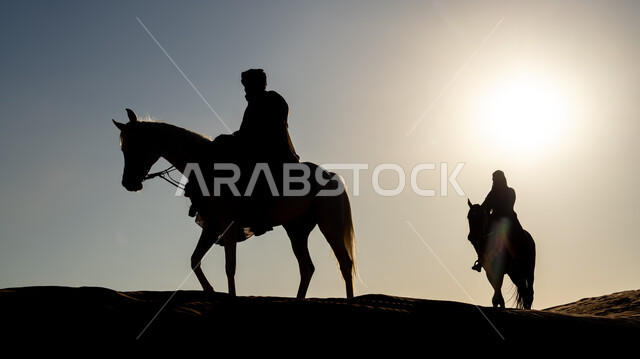 اتباع تقاليد الأجداد في حب وتربية الجياد، ذكرى تأسيس الدولة السعودية الأولى 22 فبراير، أنشطة وفعاليات سباق الأحصنة العربية في الصحراء، صورة ظلية لفارسين عربيين خليجيين سعوديين يمتطيان الخيول يتجولان فوق الرمال الذهبية في النهار، يوم بدينا 1727 م، سالوييت
