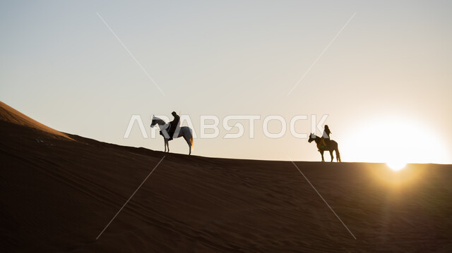 ذكرى تأسيس الدولة السعودية الأولى 22 فبراير، أنشطة وفعاليات سباق الجياد العربية في الصحراء، صورة ظلية لفارسين عربيين خليجيين سعوديين يمتطيان الخيول يتجولان فوق الرمال الذهبية في النهار، يوم بدينا 1727 م، توارث حب وتربية الحصان العربي من الأجداد، سالوييت
