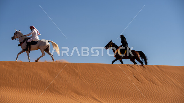 الاستمتاع بالتجول في الصحراء على ظهر الحصان، ممارسة الأنشطة الترفيهية فوق الرمال الذهبية الناعمة، الفخر بالتراث السعودي، فارس وفارسة عربيان خليجيان سعوديان يمتطيان الجياد العربية الأصيلة، ذكرى تأسيس الدولة السعودية الأولى في 22 فبرير، يوم بدينا 1727م