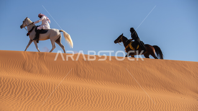الاستمتاع بالتجول في الصحراء على ظهر الحصان، ممارسة الأنشطة الترفيهية فوق الرمال الذهبية الناعمة، الفخر بالتراث السعودي، فارس وفارسة عربيان خليجيان سعوديان يمتطيان الجياد العربية الأصيلة، ذكرى تأسيس الدولة السعودية الأولى في 22 فبرير، يوم بدينا 1727م