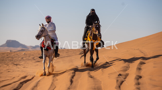ممارسة الأنشطة الترفيهية فوق الرمال الذهبية الناعمة، الفخر بالتراث السعودي، زوجان عربيان خليجيان سعوديان يمتطيان الجياد العربية الأصيلة، ذكرى تأسيس الدولة السعودية الأولى في 22 فبرير، التجول في الصحراء على ظهر الحصان، يوم بدينا 1727م