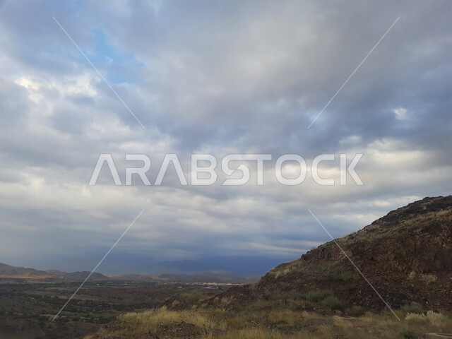 View of the cloudy sky in the winter in the Al-Baha region, terrain, peaks and mountain heights in the city of Al-Hujra, natural tourist places and areas in the cities of the Kingdom of Saudi Arabia, nature background