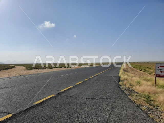 A view of the clear blue sky during the day, tigers of wild green plants on both sides of the street, a road between the city of Al-Hujra in the Al-Bahah region and the coastal road of the city of Abha in Jeddah, paved asphalt roads and streets prepared for travel in the Kingdom of Saudi Arabia