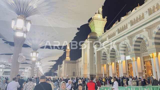 مجموعة من الزائرين في ساحة المسجد النبوي الشريف في المدينة المنورة في المملكة العربية السعودية ،المظلات الالكترونية الحديثة ,معالم دينية إسلامية مقدسة, مفهوم العبادة والتقرب الى الله، مقصد المسلمين من شتى انحاء العالم