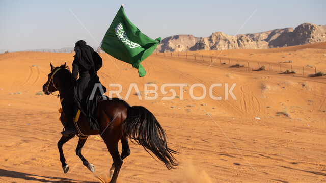 احتراف هواية الفروسية، إحياء التراث السعودي التقليدي الشعبي، رفع علم المملكة في يوم بدينا 1727م, ذكرى تأسيس الدولة السعودية الأوى في 22 فبراير, فارسة عربية خليجية سعودية ترتدي العباءة السوداء والبرقع تمتطي فرس بني أصيل, يوم العلم 11 مارس