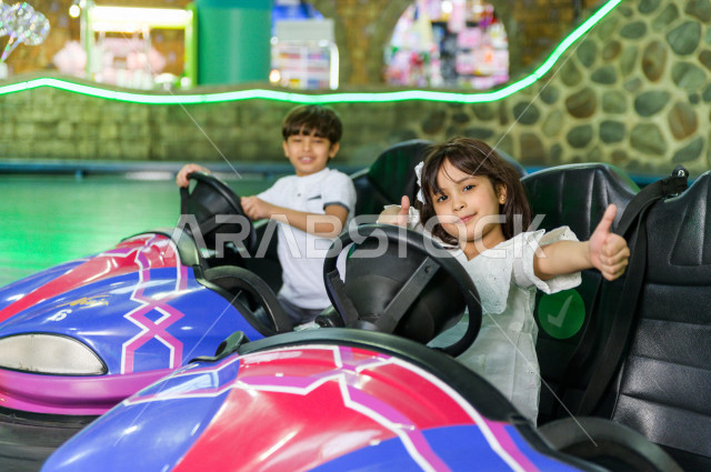 طفلان سعوديان في مدينة الألعاب ، يلعبان تصادم السيارات  ، قضاء اوقات رائعة في مدينة الملاهي ، العاب الكترونية ، التسلية و الترفيه ، الترفيه في العطلة الصيفية