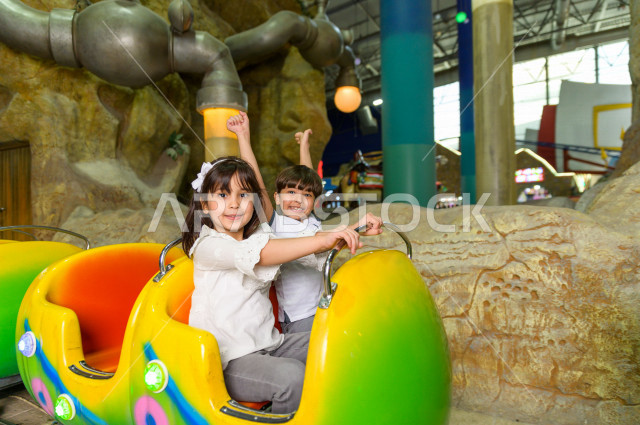 طفلان سعوديان في مدينة الألعاب ، يلعبان القطار الافعواني ، قضاء اوقات رائعة في مدينة الملاهي ، العاب الكترونية ، التسلية و الترفيه ، الترفيه في العطلة الصيفية