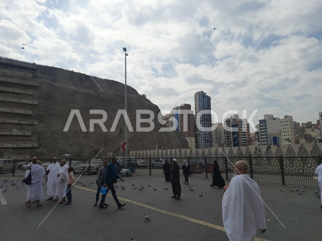 السماء الملبدة بالغيوم, الساحات الخارجية للمسجد الحرام, مقصد الزوار من جميع انحاء العالم لأداء العبادة والتقرب الى الله, تعزيز الثقافات الدينية, موقف كدي بجوار الحرم المكي في مكة المكرمة, معالم واماكن دينية مقدسة, التجمع في الساحة